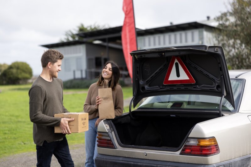Couple loading wine into a car after a cellar door tour and wine tasting.